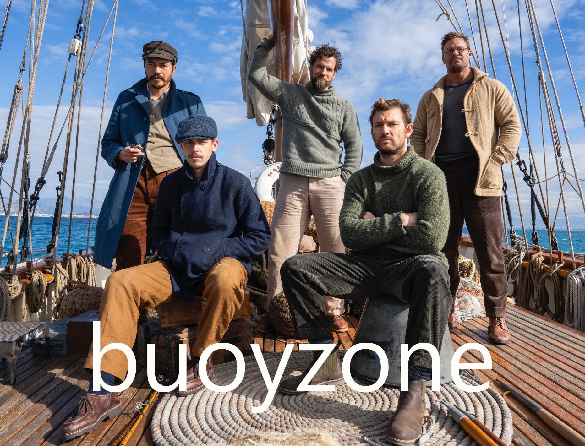 Five handsome men in a selection of rustic knits posing on the deck of a ship. Three are standing with two sitting in the front. Large text across the bottom of the photo says "buoyzone".