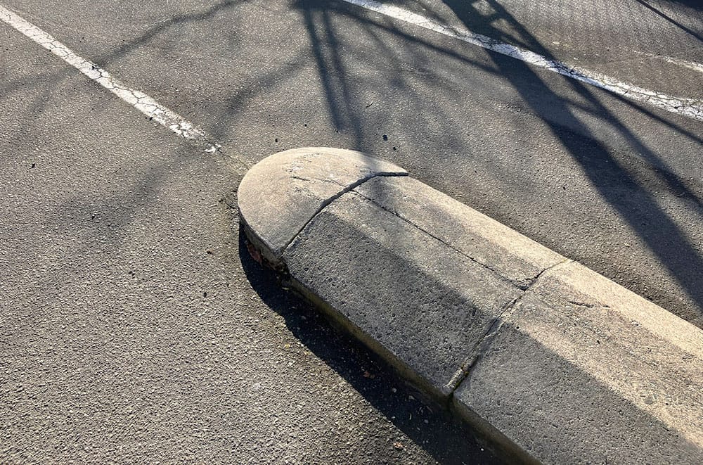 A phallus shaped concrete border with unfortunately placed white lane marking coming out of the, er, tip.